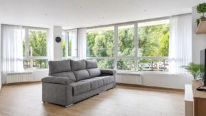 Salón luminoso del apartamento Hydros Ter Ripoll con grandes ventanales y sofá gris